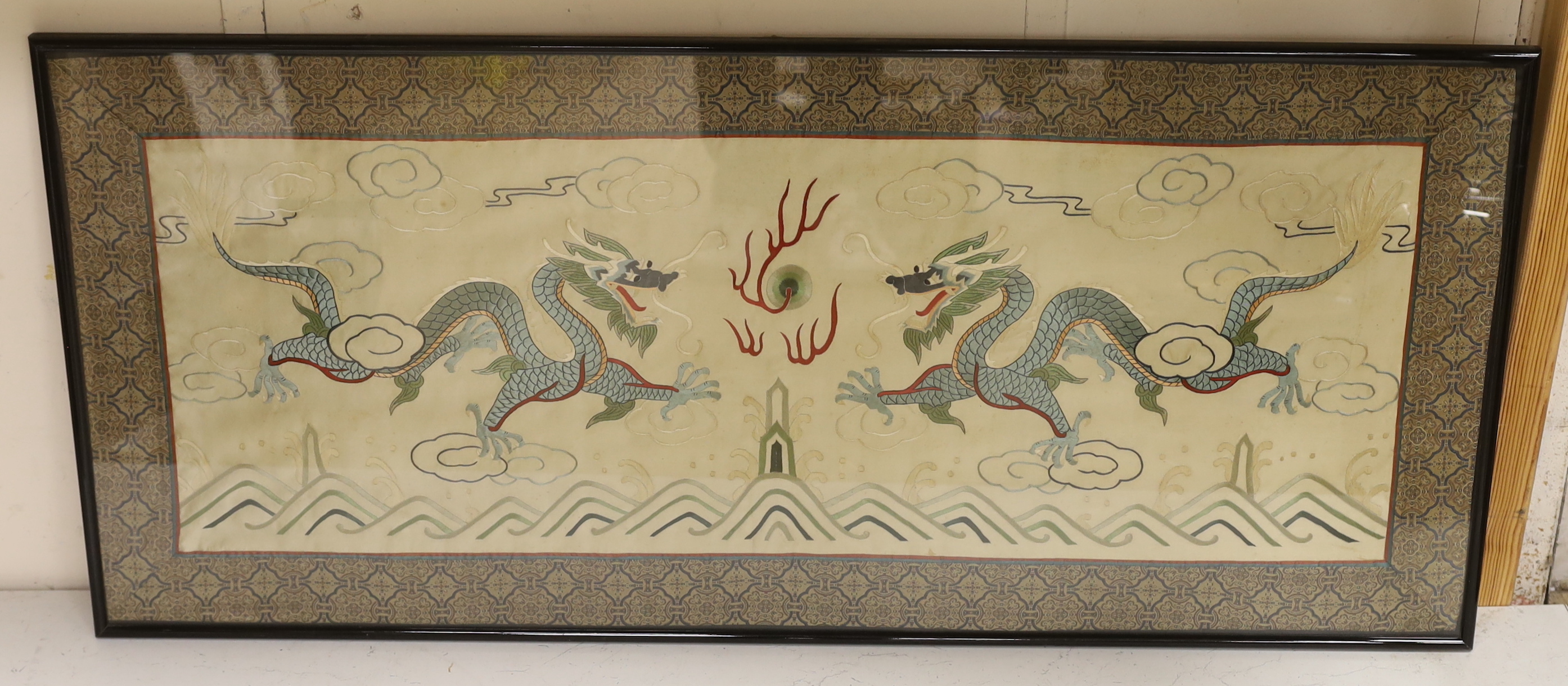 A framed 20th century Chinese silk embroidered 'dragon’ panel, with flaming pearl design, bordered with silk brocade